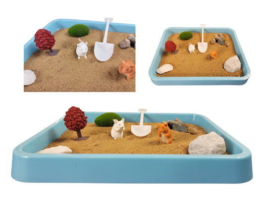 A desktop Zen garden featuring a light blue tray with sand, cute animal figurines, and various nature elements like rocks and a small tree.