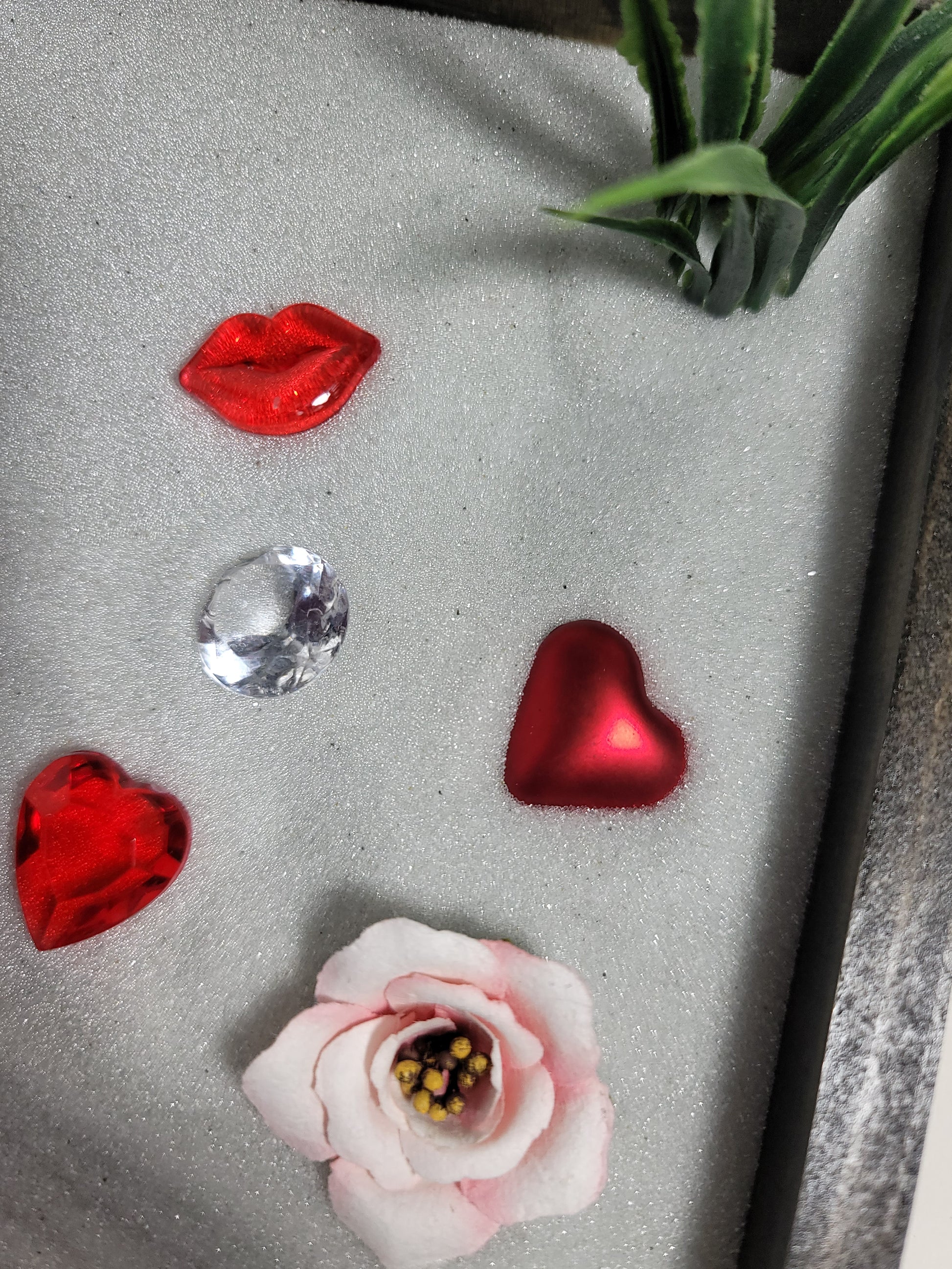 A close up of sparkling white sand and red and pink decorations