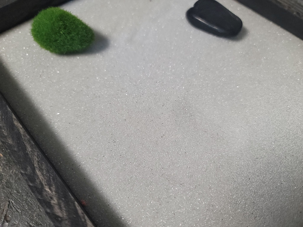 Zen garden with sparkling white sand, black polished rock, and moss rock