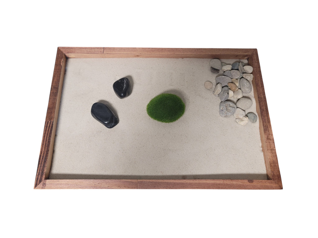 Zen garden with stones and a moss rock in a wooden tray